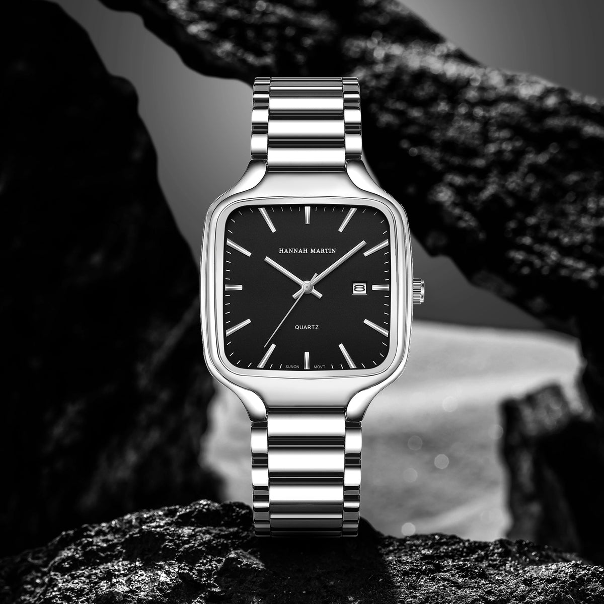 HM1691 silver-tone watch with black dial displayed against dark rocks